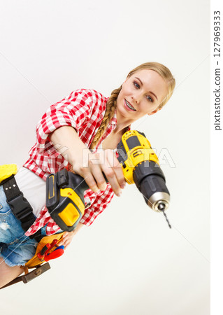 Woman using drill on wall Woman using drill on wall 127969333