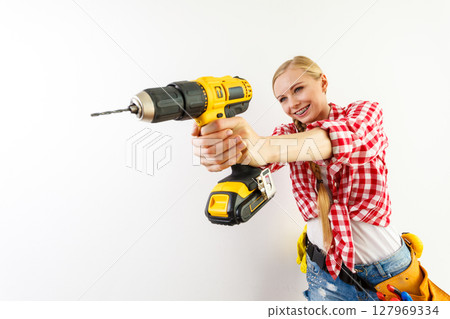 Woman using drill on wall 127969334