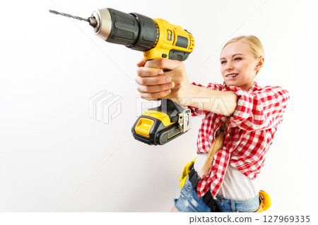 Woman using drill on wall Woman using drill on wall 127969335
