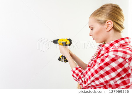 Woman using drill on wall Woman using drill on wall 127969336