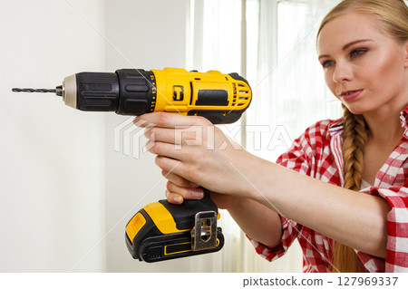 Woman using drill on wall Woman using drill on wall 127969337