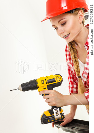Woman using drill on ladder Woman using drill on ladder 127969351