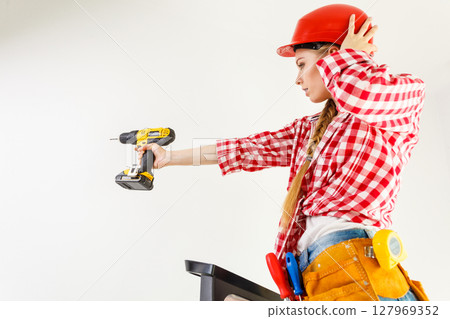Woman using drill on ladder Woman using drill on ladder 127969352