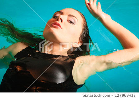 Woman floating relaxing in swimming pool water. 127969432