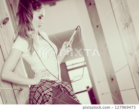 Woman with headphones choose music on smartphone. Woman with headphones choose music on smartphone. 127969473