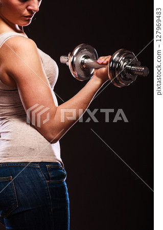 athletic woman working with heavy dumbbells 127969483