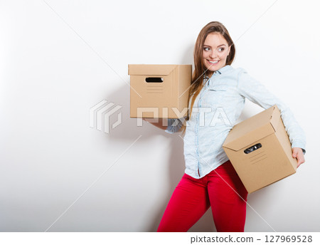 Happy woman moving into house carrying boxes. 127969528