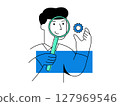 A quality control inspector holds magnifying glass and gear while smiling, wearing gloves, representing inspection and assurance in manufacturing environment 127969546