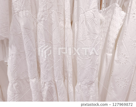 White embroidered dresses hanging in fashion store in prague 127969872