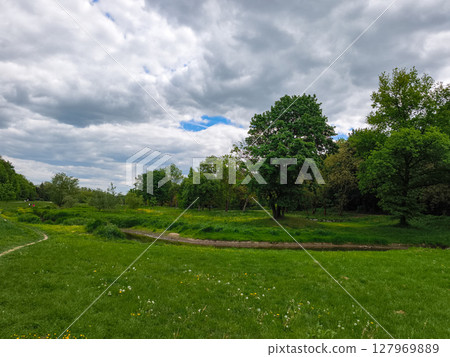 Stromovka park in prague showing lush green grass and trees under cloudy sky 127969889