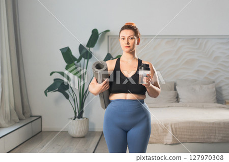 Yoga fitness sport workout training. Woman hold yoga mat bottle water ready for practicing yoga at home. Plus size female doing sports indoor. Girl in sportswear have training workout for weight loss 127970308