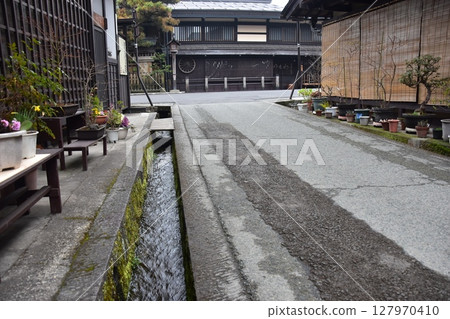 Spring in Gifu Prefecture, Japan. Old street in the center of Takayama city. Historic Japanese houses and small waterway. Beautiful potted plants on the roadside. Spring in Gifu Prefecture, Japan. Old street in the center of Takayama city. Historic Japanese houses and small waterway. Beautiful potted plants on the roadside. 127970410