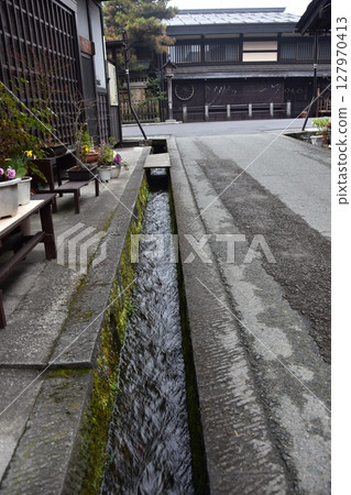 Spring in Gifu Prefecture, Japan. Old street in the center of Takayama city. Historic Japanese houses and small waterway. Beautiful potted plants on the roadside. Spring in Gifu Prefecture, Japan. Old street in the center of Takayama city. Historic Japanese houses and small waterway. Beautiful potted plants on the roadside. 127970413