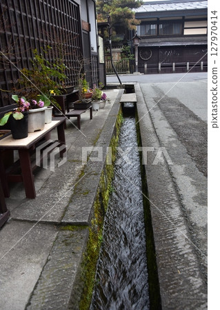 Spring in Gifu Prefecture, Japan. Old street in the center of Takayama city. Historic Japanese houses and small waterway. Beautiful potted plants on the roadside. Spring in Gifu Prefecture, Japan. Old street in the center of Takayama city. Historic Japanese houses and small waterway. Beautiful potted plants on the roadside. 127970414