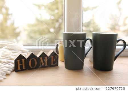 Still life home decor in a cozy house with wooden letters with the inscription home. The concept of decor and comfort. two cups with hot tea. selective focus Still life home decor in a cozy house with wooden letters with the inscription home. The concept of decor and comfort. two cups with hot tea. selective focus 127970720