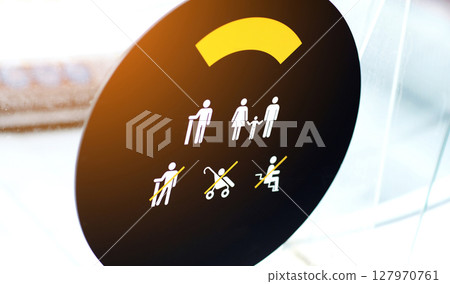 warning signs on an escalator at the shopping mall in Spain, safety concept. Sign of passage with a baby carriage and sitting is prohibited on the escalator. Por su seguridad warning signs on an escalator at the shopping mall in Spain, safety concept. Sign of passage with a baby carriage and sitting is prohibited on the escalator. Por su seguridad 127970761