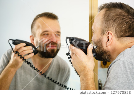 Man shaving trimming his beard Man shaving trimming his beard 127970838