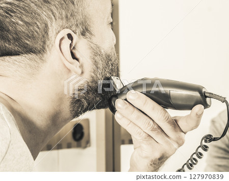Man shaving trimming his beard Man shaving trimming his beard 127970839