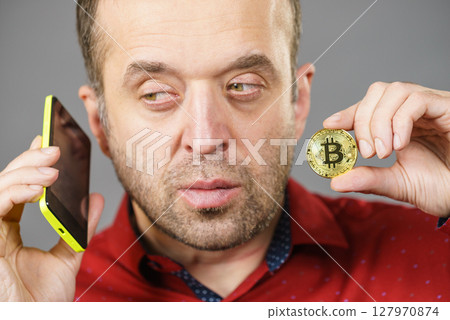 Man with bitcoin talking on phone 127970874