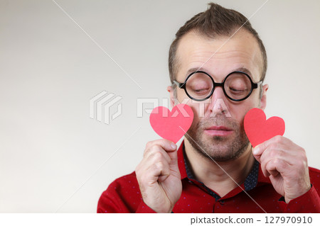 Sad man holding two red hearts. 127970910