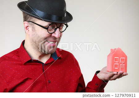 Man wearing funny eyeglasses holding house 127970911