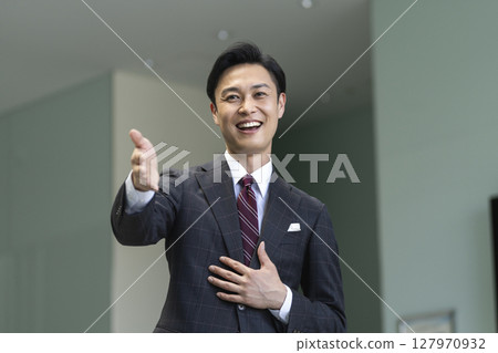 A man in his 40s wearing a suit speaking with gestures 127970932