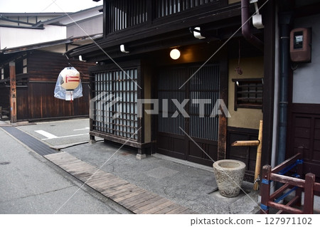 日本岐阜縣高山市上三之町的古老街景。古老的房屋和裝飾燈籠喚起人們的歷史感。春季高山祭期間的風景。 日本岐阜縣高山市上三之町的古老街景。古老的房屋和裝飾燈籠喚起人們的歷史感。春季高山祭期間的風景。 127971102