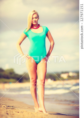 Woman walking on beach wearing swimsuit 127971151