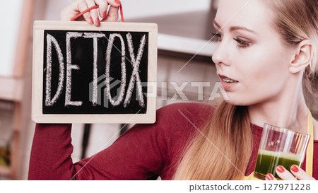 Woman in kitchen holding vegetable smoothie juice 127971228
