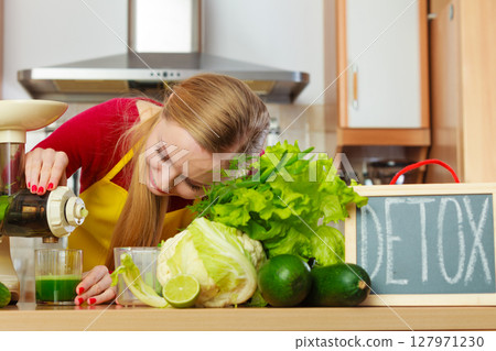 Woman in kitchen making vegetable smoothie juice Woman in kitchen making vegetable smoothie juice 127971230