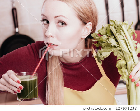 Woman in kitchen holding vegetable smoothie juice Woman in kitchen holding vegetable smoothie juice 127971238