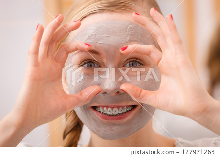 Woman with clay mud mask having fun 127971263
