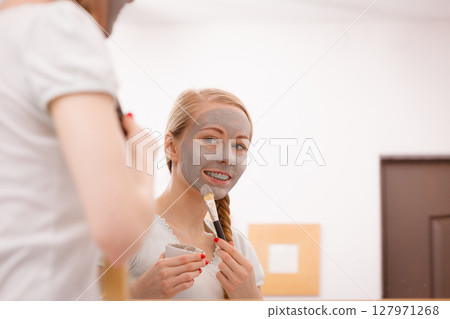 Woman with grey clay mud mask on her face 127971268