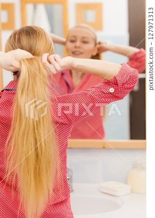 Woman combing her long hair in bathroom Woman combing her long hair in bathroom 127971313