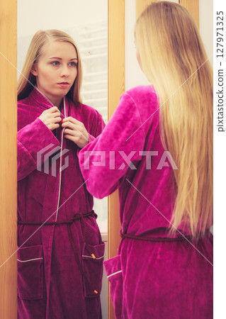Woman looking at her reflection in mirror Woman looking at her reflection in mirror 127971325