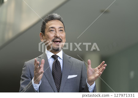 一位穿著西裝的老人用手勢說話 一位穿著西裝的老人用手勢說話 127971331
