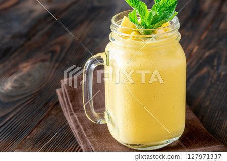 Chilled mango lassi in mason jar topped with mint and mango cubes 127971337