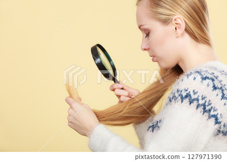 Sad woman looking at damaged hair ends. Sad woman looking at damaged hair ends. 127971390