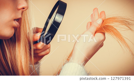 Sad woman looking at damaged hair ends. Sad woman looking at damaged hair ends. 127971391