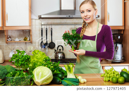 Woman housewife in kitchen with green vegetables Woman housewife in kitchen with green vegetables 127971405