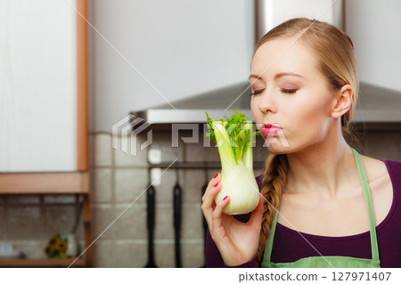 Woman in kitchen holds raw fennel bulb vegetable Woman in kitchen holds raw fennel bulb vegetable 127971407