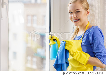 Woman cleaning window at home Woman cleaning window at home 127971441