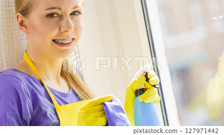 Girl cleaning window at home 127971442