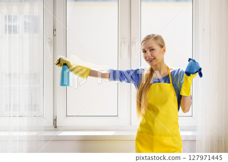 Woman cleaning window at home Woman cleaning window at home 127971445
