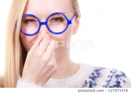 Nerdy woman holding nose smelling bad scent Nerdy woman holding nose smelling bad scent 127971476
