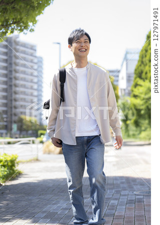 A man in his 40s walking down the street 127971491