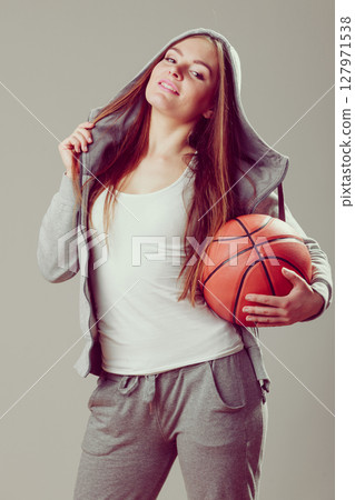 Sporty teen girl in hood holding basketball. Sporty teen girl in hood holding basketball. 127971538