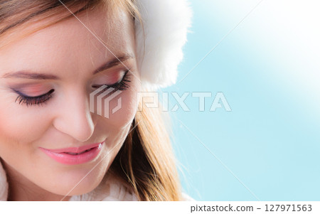 Happy woman in white earmuffs on blue 127971563