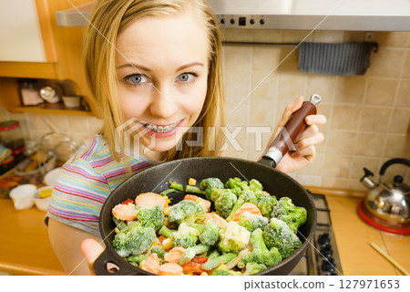 Woman cooking stir fry frozen vegetable on pan 127971653