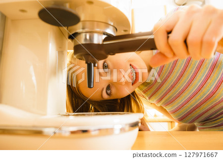 Woman in kitchen making coffee from machine Woman in kitchen making coffee from machine 127971667